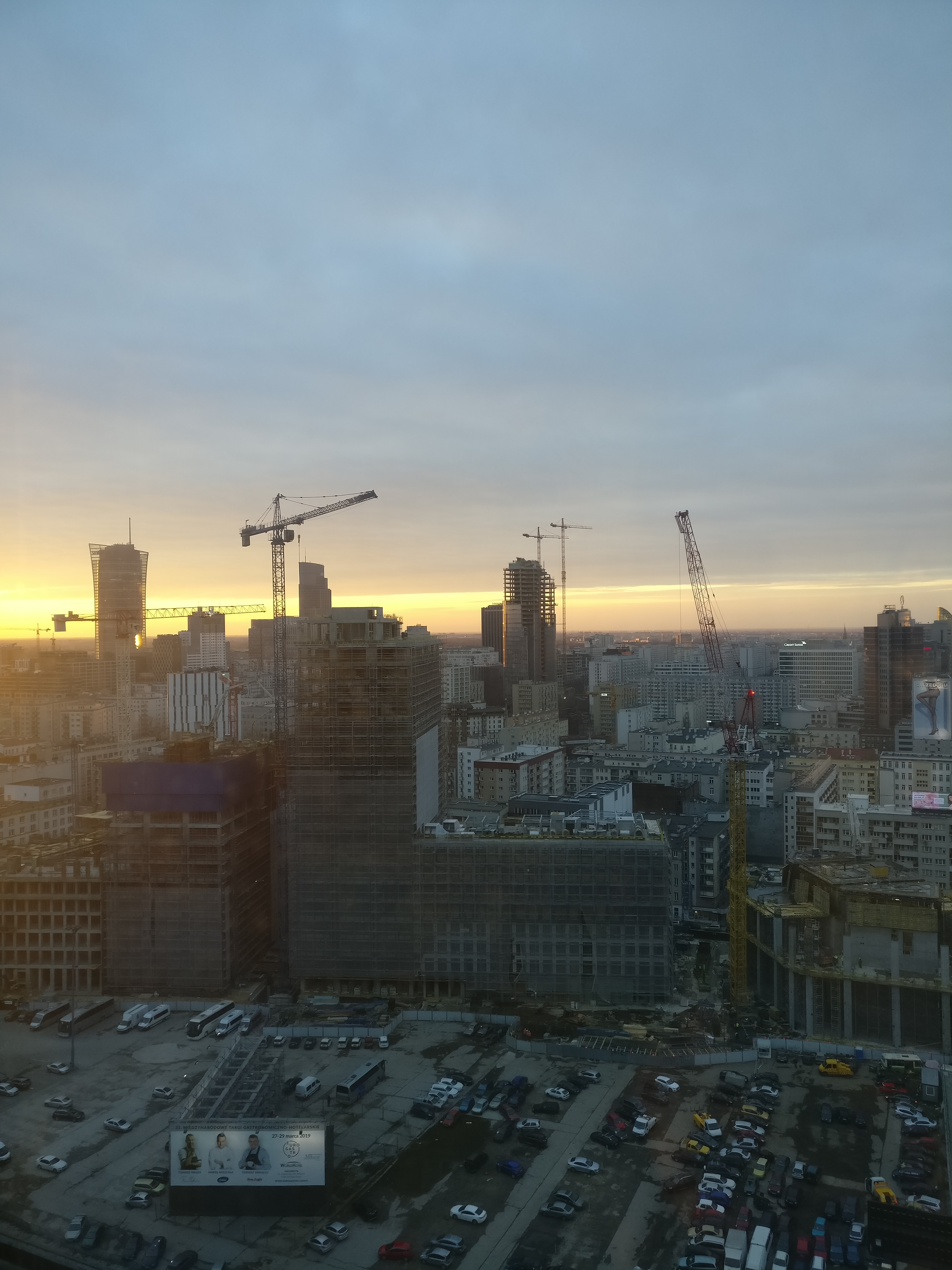 Construction cranes silhouetted against sunset sky