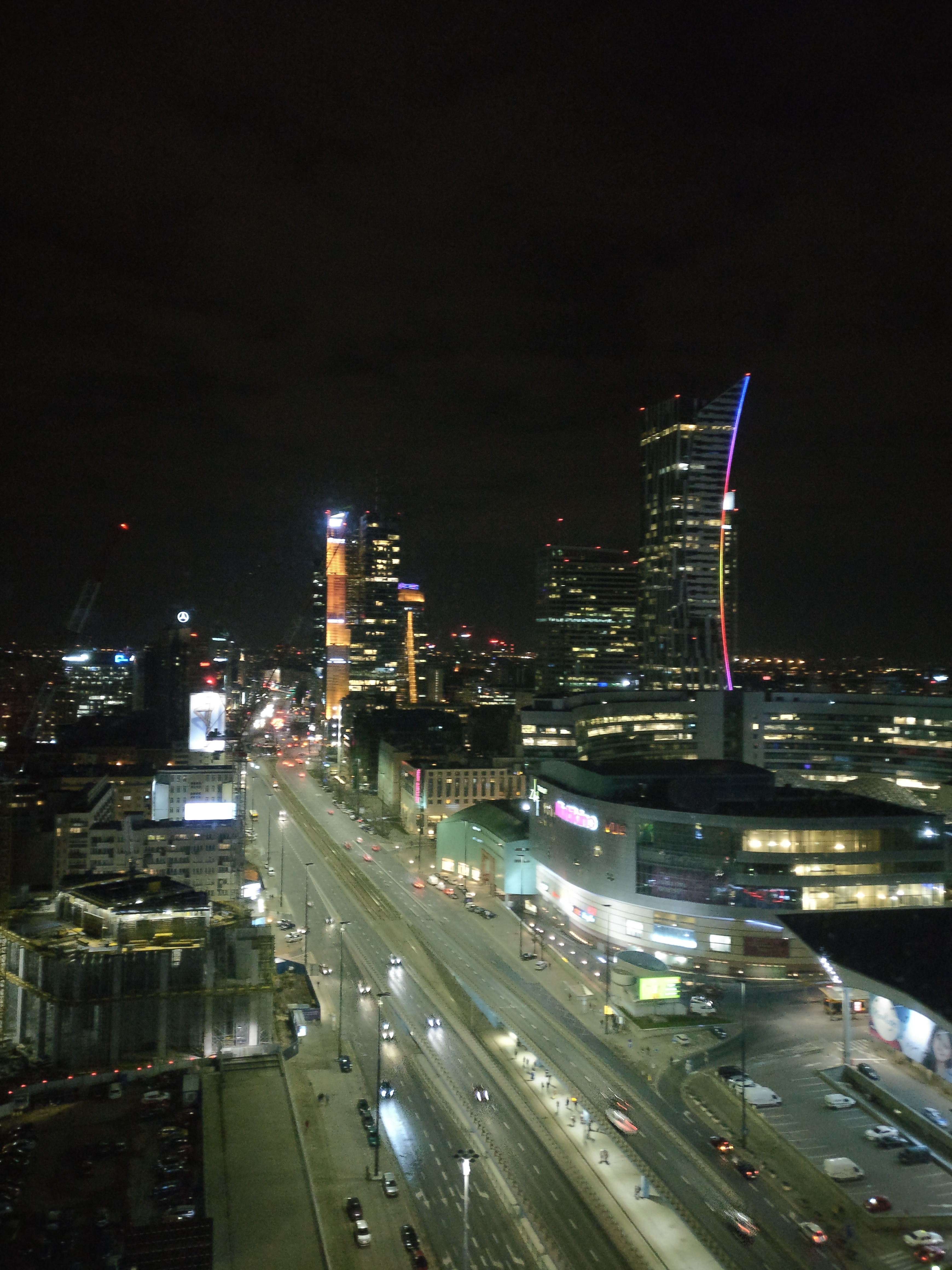 Night view with Warsaw Spire's LED display cycling through colors